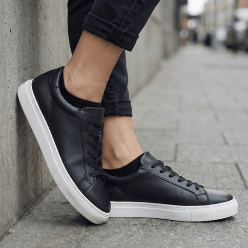 Zwarte leren sneakers met witte zolen gedragen met Sukats sneakersokken.