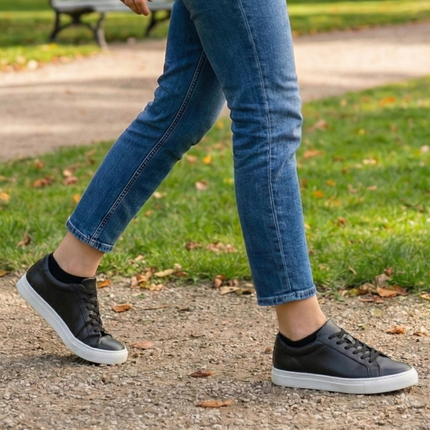 Persoon in blauwe jeans en zwarte sneakers met Sukats sneakersokken tijdens een wandeling.